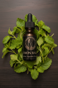2oz amber dropper bottle of Lemon Balm Glycerite surrounded by fresh lemon balm leaves